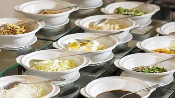 A buffet table with various dishes in white bowls, each with a spoon.