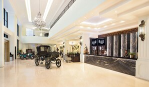 A spacious lobby with a classic carriage, a reception desk, and a grand chandelier. - Grand Rohan Jogja (Banguntapan)