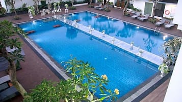 A rectangular pool with a clear blue water surface, surrounded by lounge chairs and potted plants.