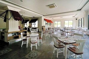Un restaurante espacioso con numerosas mesas y sillas, ventanas amplias y un diseño interior moderno.