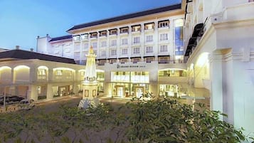 A hotel with a central courtyard, a prominent fountain, and a sign reading "Grand Rohan Jogja."