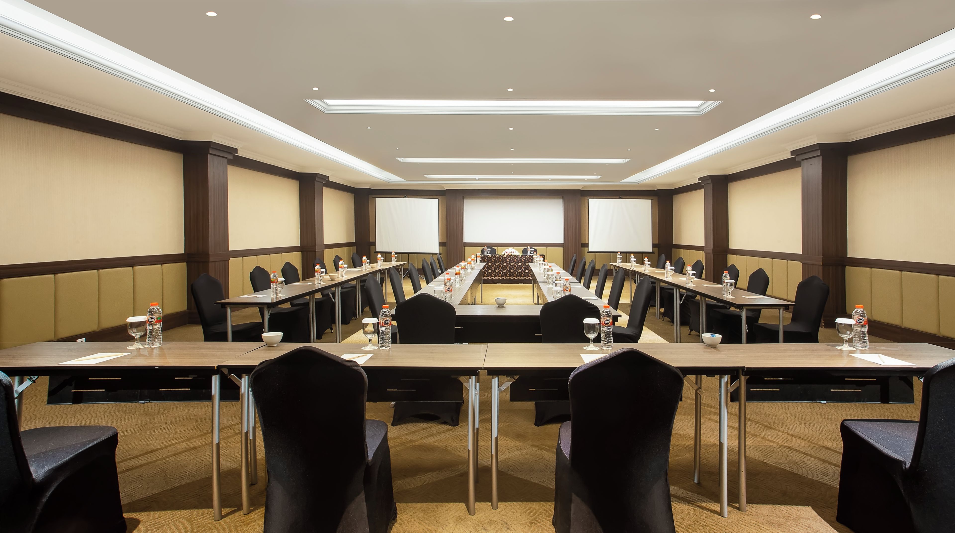 Un salón de conferencias con una mesa larga, sillas y un atril.