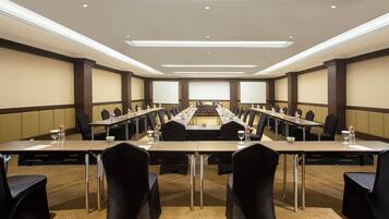 Un salón de conferencias con una mesa larga, sillas y un atril.