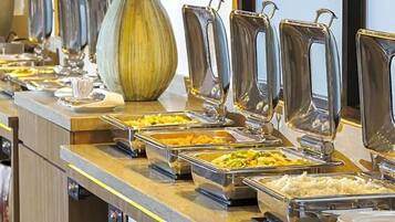 A buffet with various food items in metal containers, a large vase, and a modern counter design.