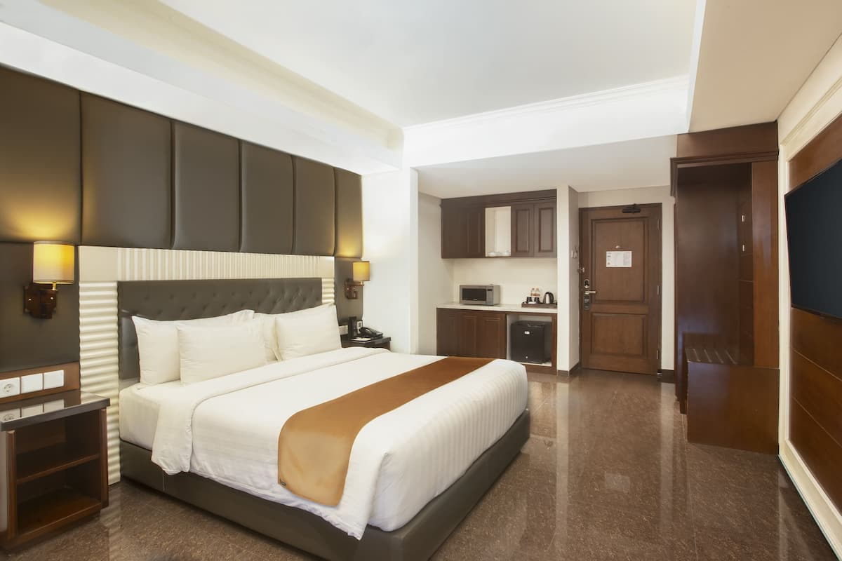 Quarto de hotel com uma cama grande, uma escrivaninha, micro-ondas e televisão.