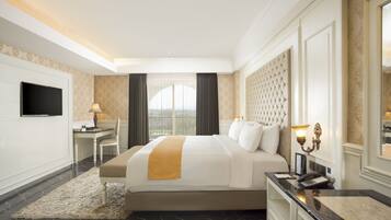 A hotel room with a large bed, a desk, a television, and a view of the city.