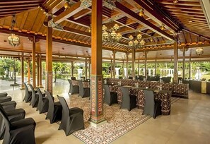 A covered outdoor seating area with tables and chairs, decorative columns, and hanging lanterns. - Grand Rohan Jogja (Banguntapan)