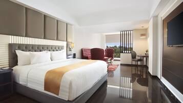 A modern hotel room with a large bed, a desk, a chair, and a TV.