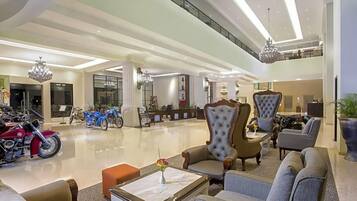 Un vestíbulo amplio con techos altos, candelabros modernos y una zona de estar con sillones y sofás cómodos.