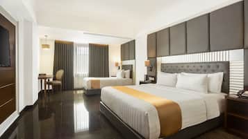 A hotel room with a large bed, a smaller bed, a desk, and a TV.