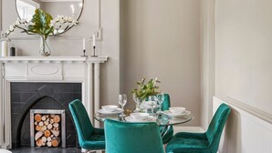 A dining area with a fireplace, a round table set for four, and teal chairs.