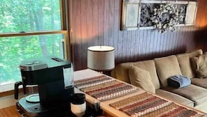 A cozy living area with a wood-burning stove, a sofa, a coffee table, and a view of the outdoors. - Barnaminium Upstairs Loft (Pickens)