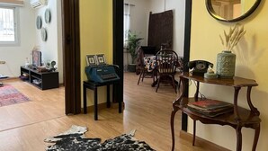 A living room with a wooden floor, a typewriter, a dining table with chairs, a mirror, and a vase with dried plants. - Vintage Vibrant Space ! (Cairo)