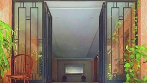 A set of marble steps leading to a doorway with a wooden chair and potted plants on either side. - Vintage Vibrant Space ! (Cairo)