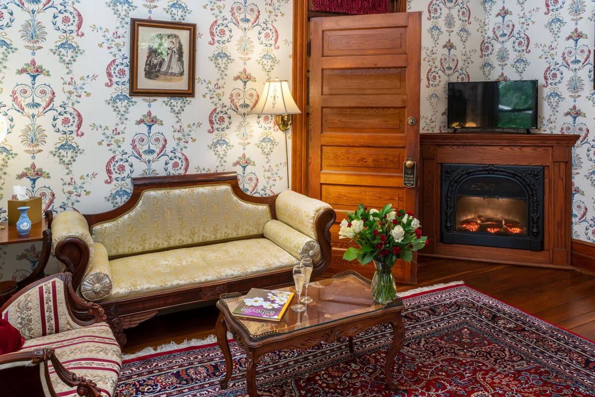 Un salon traditionnel avec un canapé, une cheminée, un téléviseur et une lampe décorative.