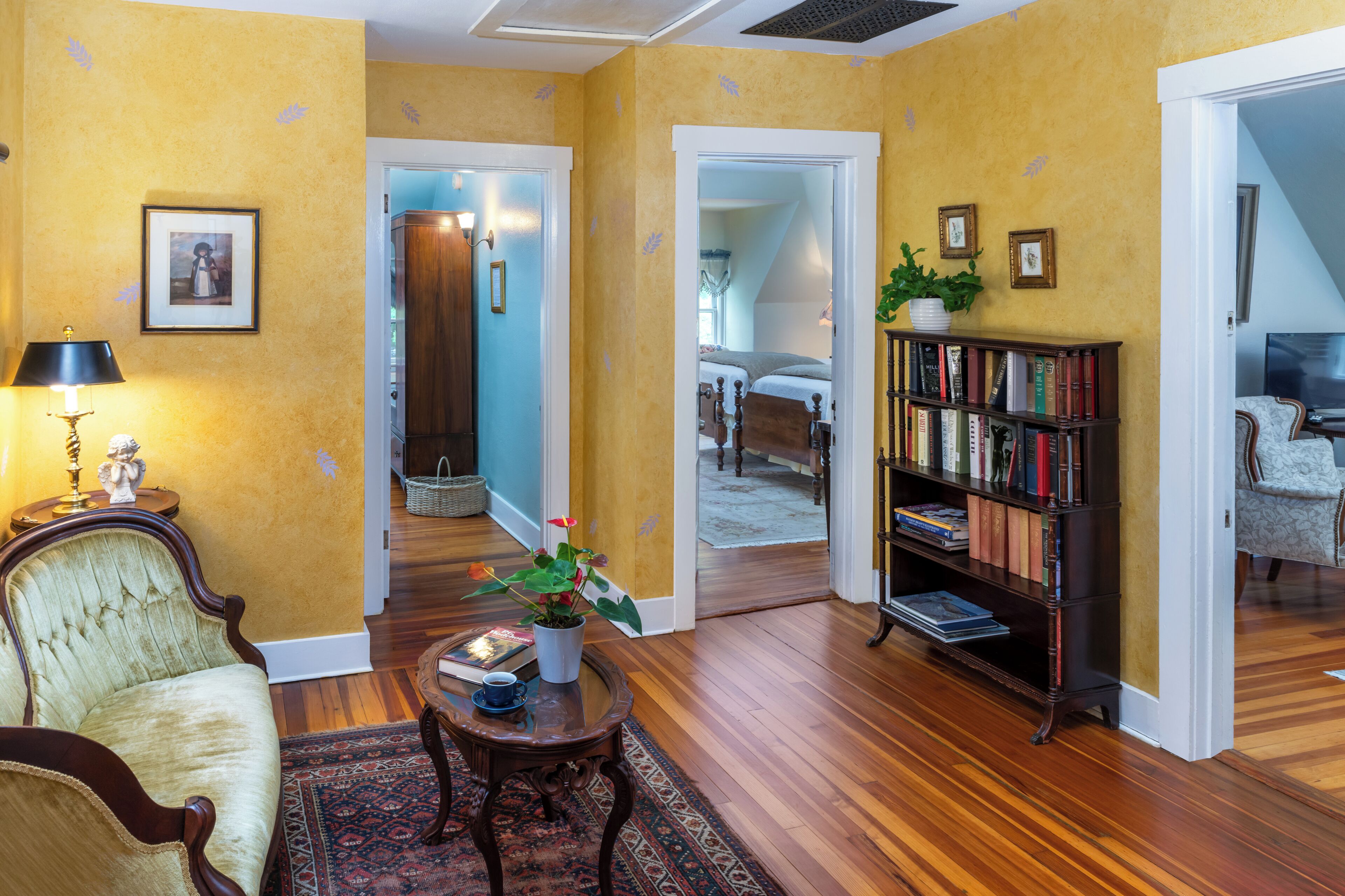 A living room with a sofa, a coffee table, a bookshelf, and a staircase leading to another room.