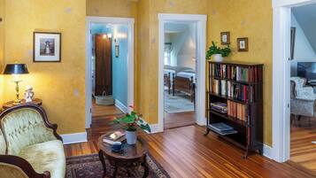 A living room with a sofa, a coffee table, a bookshelf, and a staircase leading to another room.