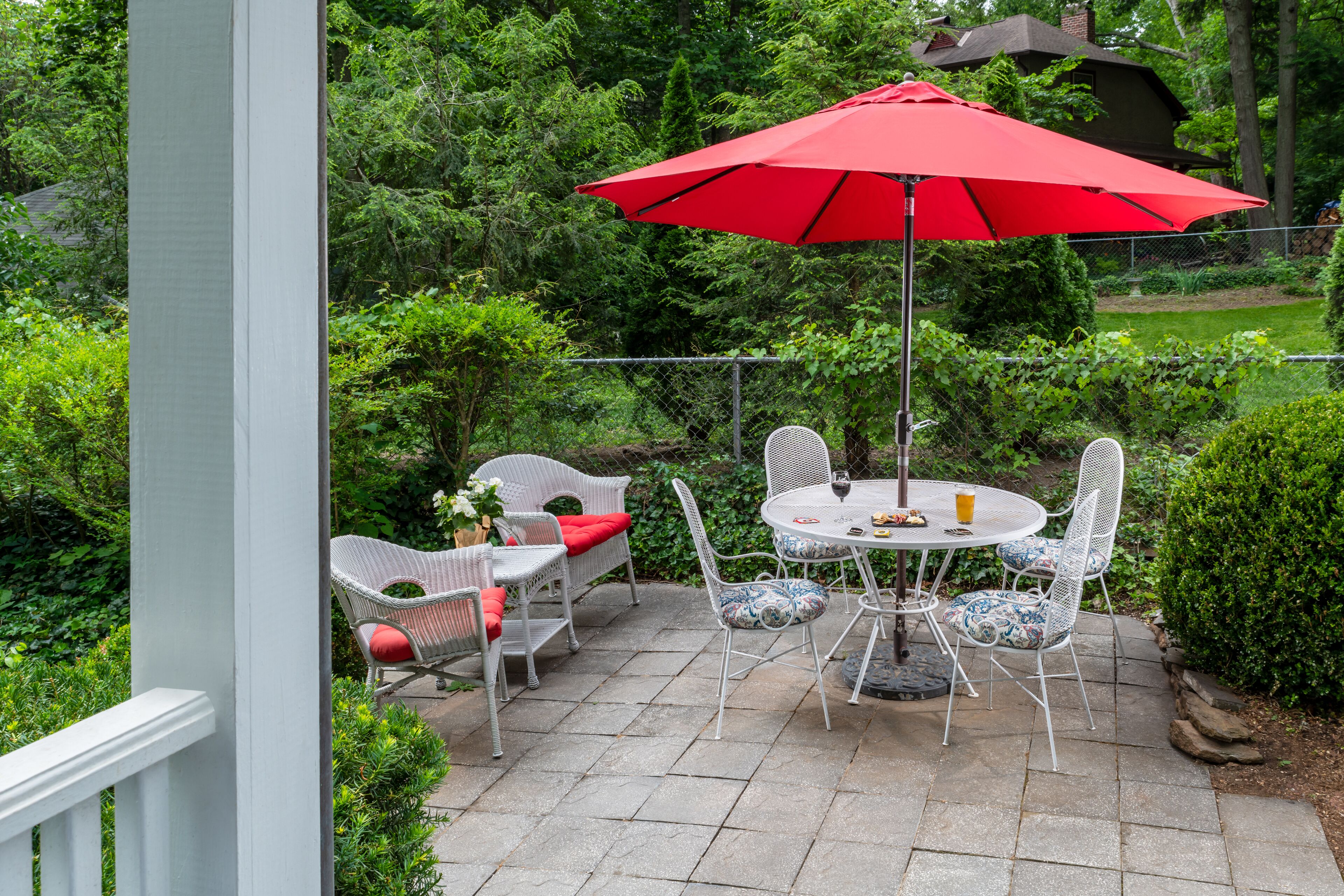 Eine Terrasse mit Tisch und Stühlen, umgeben von Grünpflanzen.