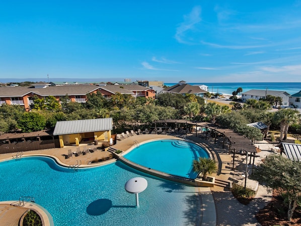 En resort med en stor swimmingpool, loungeområder og havudsigt.