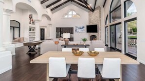 A spacious living area with a long dining table, white sofas, and a fireplace. - Scottsdale Diamond Mtn Oasis+Waterslide+Pickleball (Scottsdale)