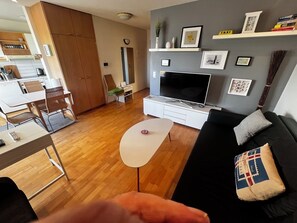 Een moderne woonkamer met een televisie, bank en een eethoek.