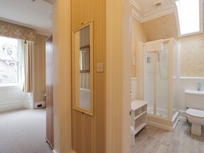 Une salle de bain avec une douche, des toilettes et un miroir.