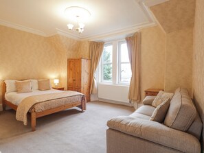 Une chambre avec un grand lit, une armoire en bois, une fenêtre avec des rideaux et un canapé.