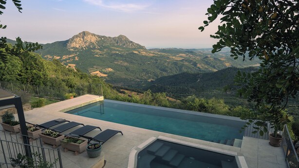 A swimming pool with a mountain view, lounge chairs, and planters.