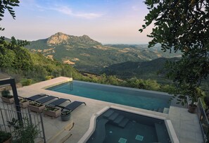 A swimming pool with a mountain view, lounge chairs, and planters. - Luxurious, Private Villa in Gaucin with Breathtaking Views to Morocco (Gaucín)
