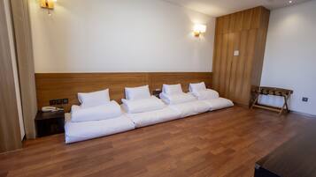 Habitación de hotel con una cama grande, cabecero de madera, dos mesitas de noche y un banco junto a la ventana.