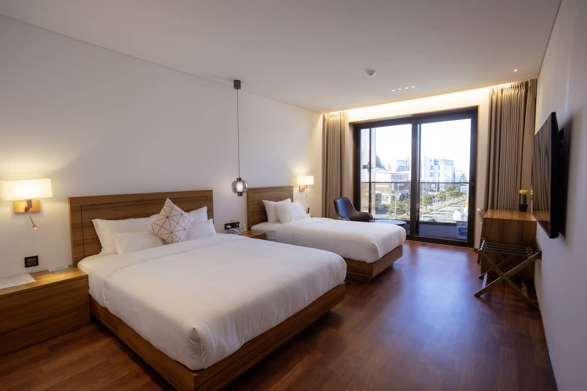 A hotel room with two beds, a city view, a TV, and a desk with a chair.