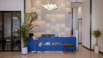 A reception desk with a blue counter, a potted plant, and a hanging light fixture.
