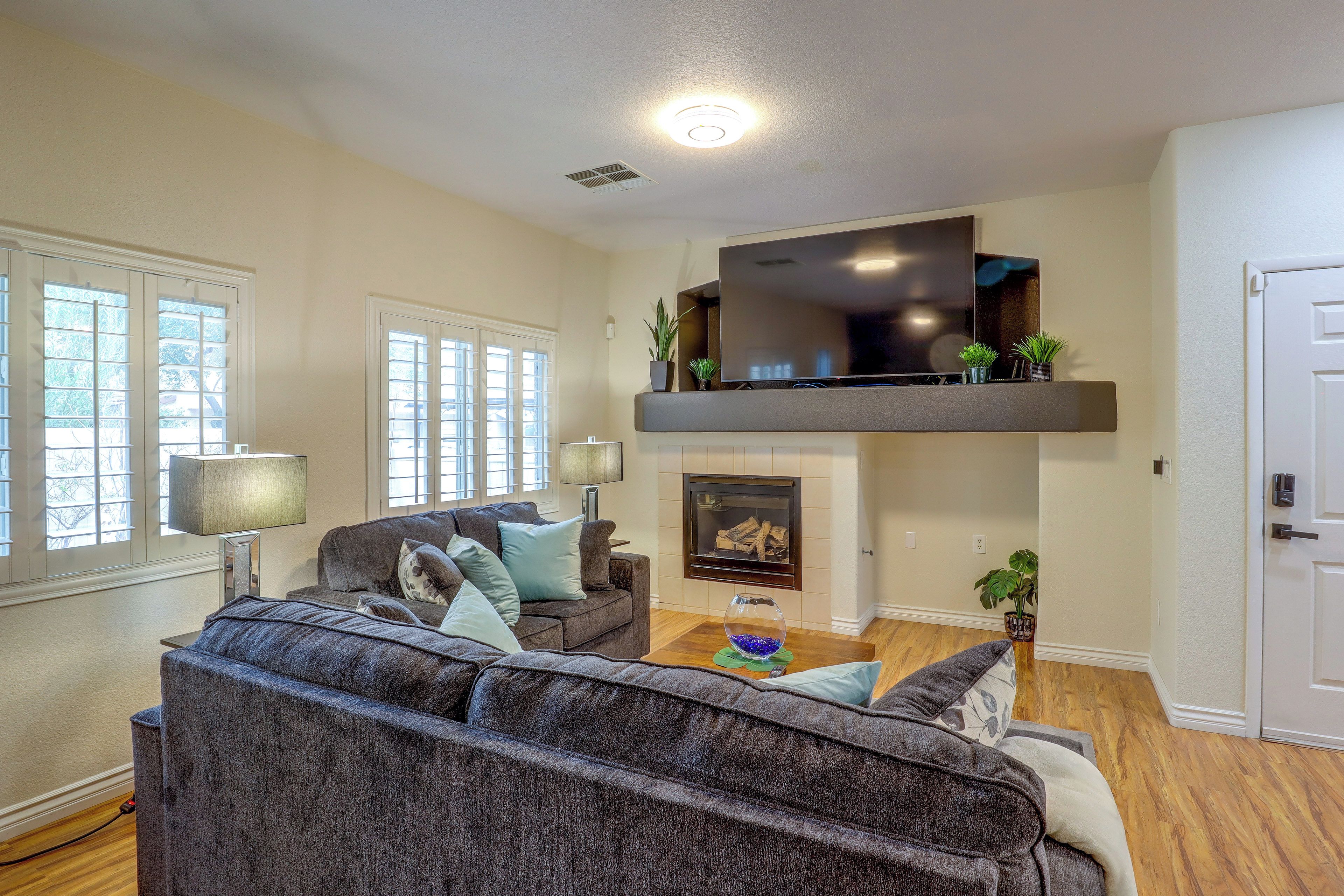 A living room with a sofa, a flat-screen TV mounted on a wall, a fireplace, and a door.