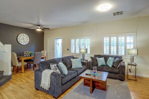 Ein Wohnzimmer mit zwei Sofas, einem Couchtisch, einem Essbereich mit Tisch und Stühlen sowie einer großen Wanduhr.