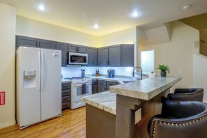 A modern kitchen with grey cabinets, a built-in microwave, a gas stove, and a marble countertop. - Pool & Spa Access! Henderson Monthly Stay (Henderson)
