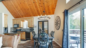 A spacious kitchen with wooden cabinets, a dining area with a large table and chairs, and a view of the outdoors through a sliding glass door. - Serene Cabin Retreat Between Murphys & Arnold (Murphys)