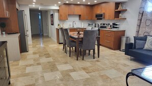 Une cuisine moderne avec des meubles en bois, un coin repas avec une table et des chaises, et un salon avec un canapé.