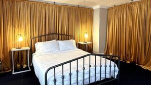 Ein Hotelzimmer mit Bett, Vorhängen, Deckenventilator und Nachttischlampen.