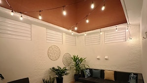 A cozy patio area with a round table, chairs, a sofa, and string lights. - 2 Bedroom APT w/ Ocean & Condado Lagoon views, restaurants, walk to the beach... (San Juan)