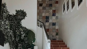 A staircase with terracotta tiles, a wooden bench, and a large potted plant. - 2 Bedroom APT w/ Ocean & Condado Lagoon views, restaurants, walk to the beach... (San Juan)