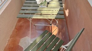 A balcony with a small table and two chairs, a white vase with flowers, and a white railing. - 2 Bedroom APT w/ Ocean & Condado Lagoon views, restaurants, walk to the beach... (San Juan)