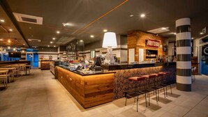 Zona de bar moderna con mostrador de madera, taburetes y un cartel que dice 