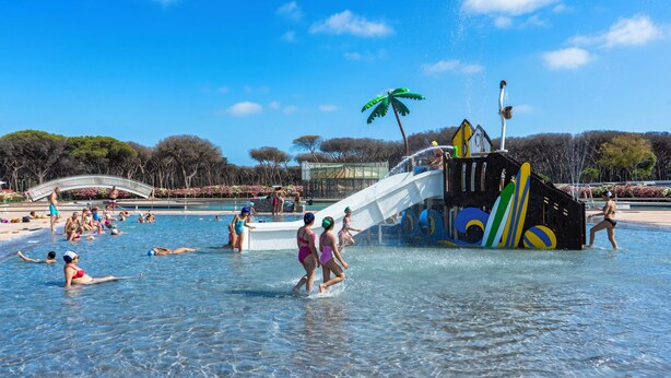 Un parque acuático con una piscina grande, una tobogán y una zona de playa.