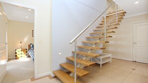 A modern staircase with wooden steps and a metal handrail, leading to a white door. - Mariners Mark 4 - Your Ultimate Getaway in Hawks Nest (Hawks Nest)