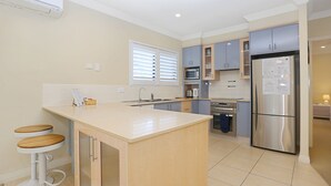 A modern kitchen with a central island, stainless steel appliances, and light-colored cabinetry. - Mariners Mark 4 - Your Ultimate Getaway in Hawks Nest (Hawks Nest)