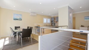 A modern apartment with a dining area, kitchen, and a staircase. - Mariners Mark 4 - Your Ultimate Getaway in Hawks Nest (Hawks Nest)