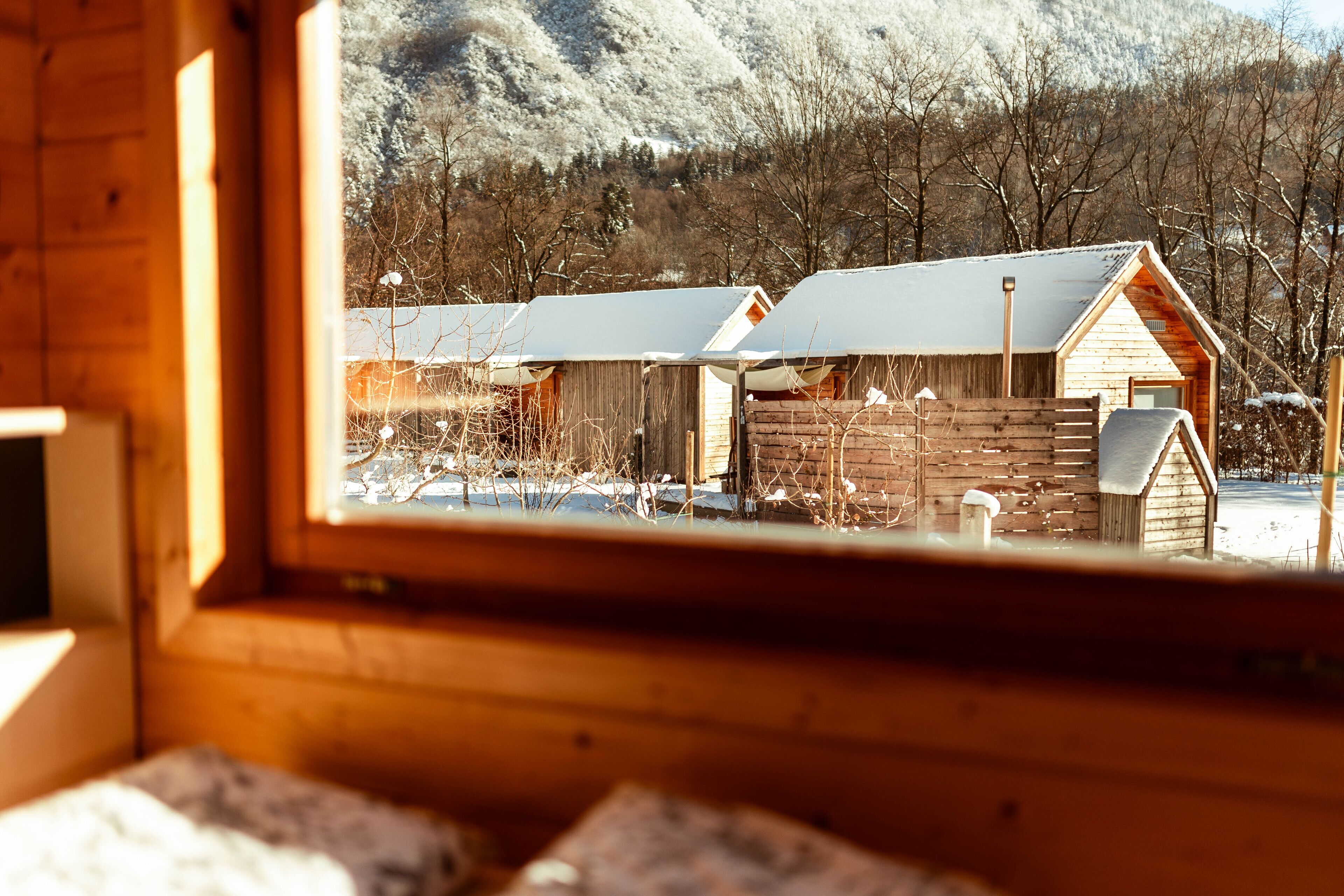A wooden cabin with a view of a snowy landscape and mountains.