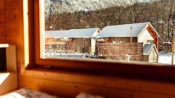 A wooden cabin with a view of a snowy landscape and mountains.