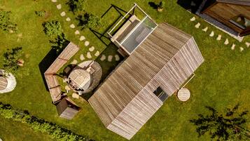 Vue aérienne d’une terrasse en bois dotée d’une enceinte en verre, entourée d’une pelouse et d’un jardin bien entretenus.