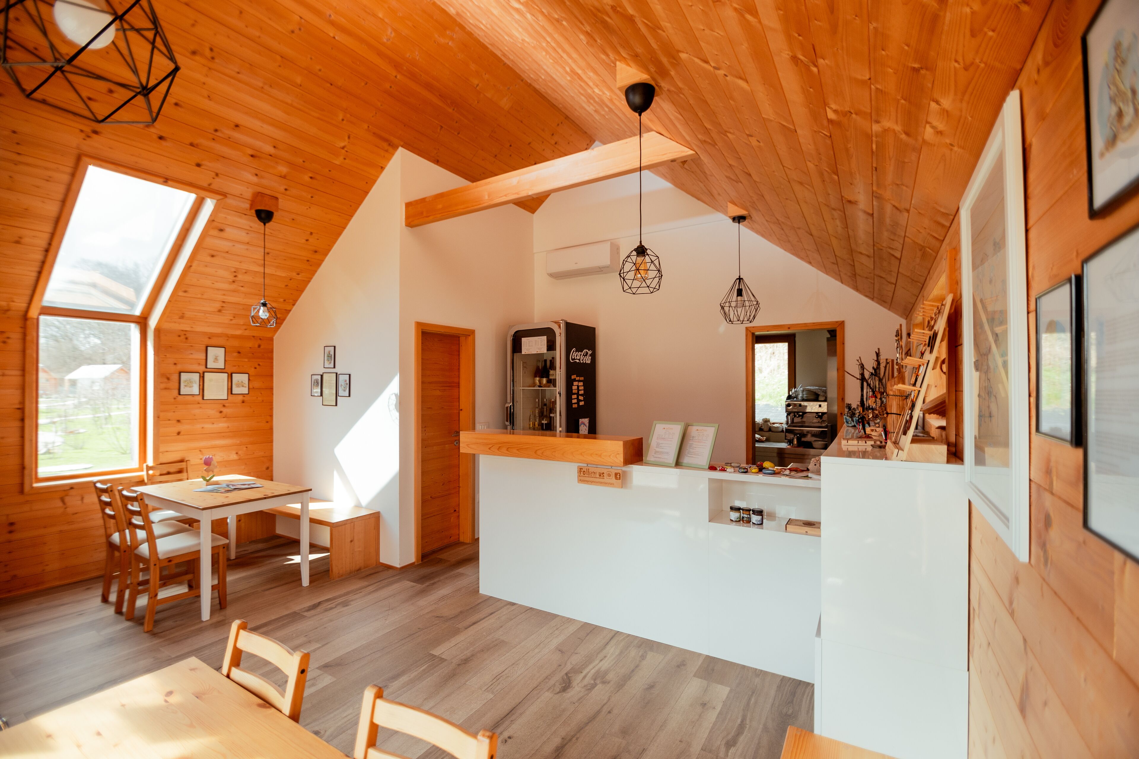 A cozy wooden interior with a dining area, a kitchen counter, and a large window providing natural light.